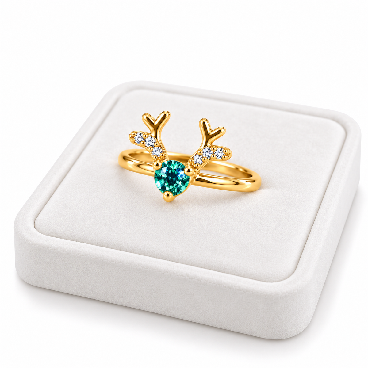 Angled white velvet jewelry tray displaying a gold-plated sterling silver reindeer ring with a round green moissanite gemstone, three-prong setting, and CZ-accented antlers.