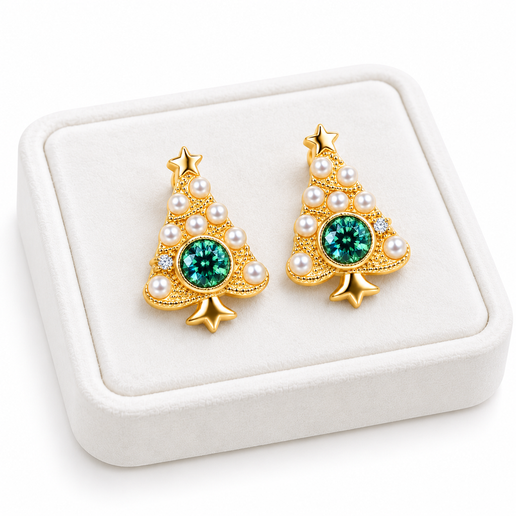 Angled white velvet tray displaying two gold Christmas tree earrings with green moissanite centers and pearl-style ornaments.