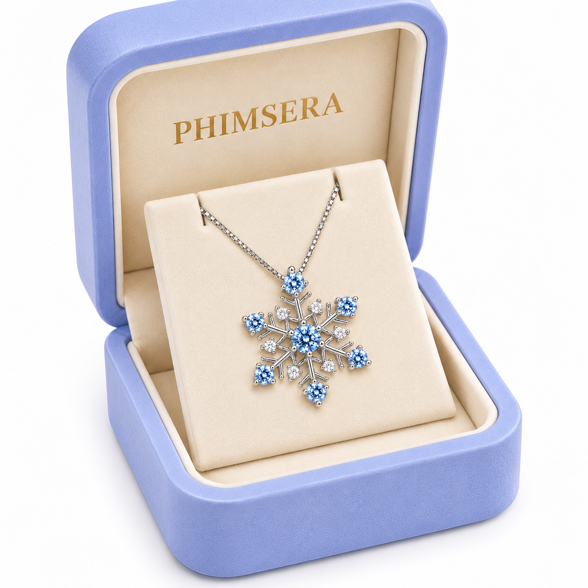 Three-quarter view of an icy blue moissanite snowflake necklace presented in an open periwinkle Phimsera jewelry box with cream velvet lining, gold branding and elegant gift-ready presentation against a pure white background.