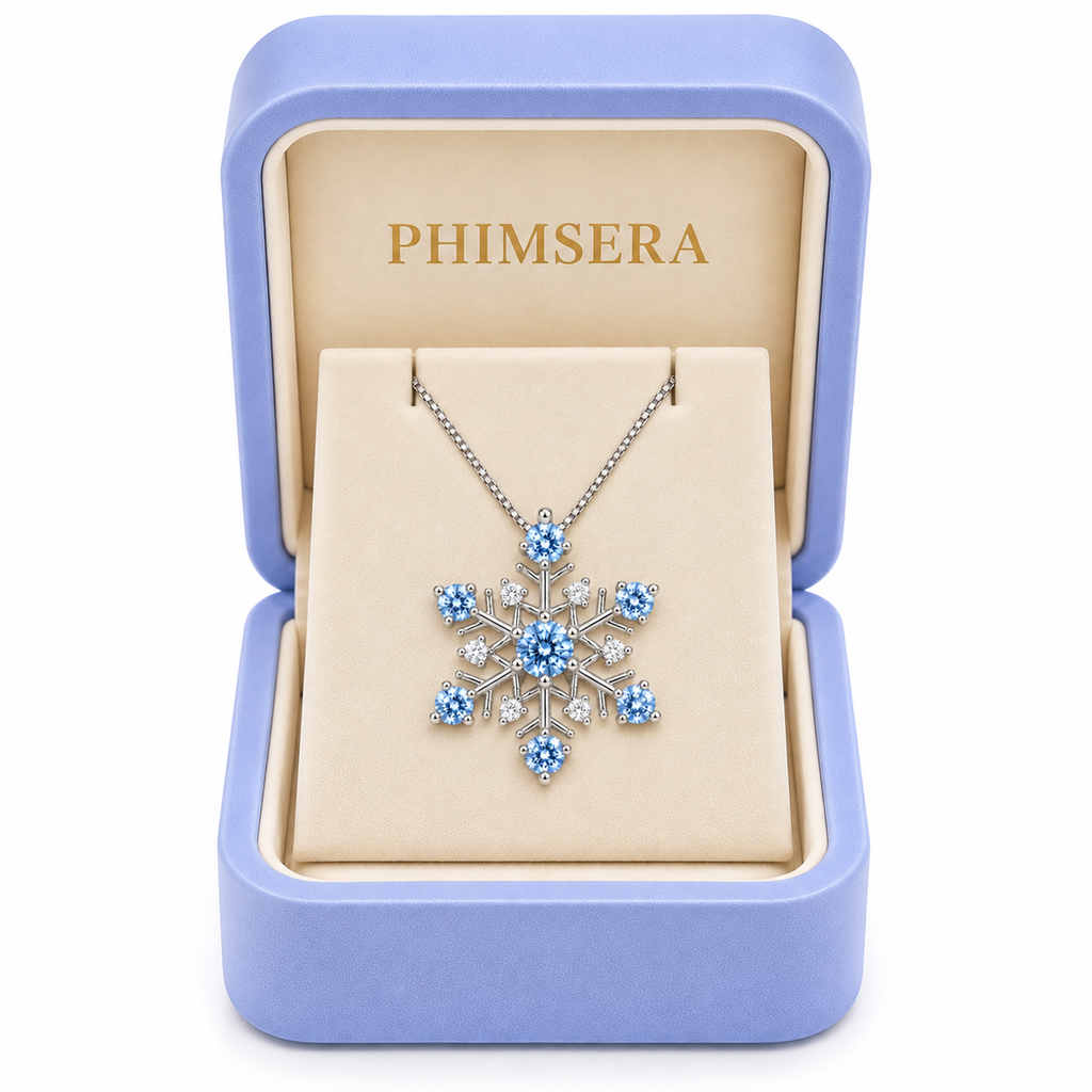 Icy blue moissanite snowflake necklace displayed inside a periwinkle Phimsera jewelry gift box with ivory velvet interior and gold PHIMSERA lettering, featuring seven sparkling blue moissanite gemstones and white cubic zirconia accents.