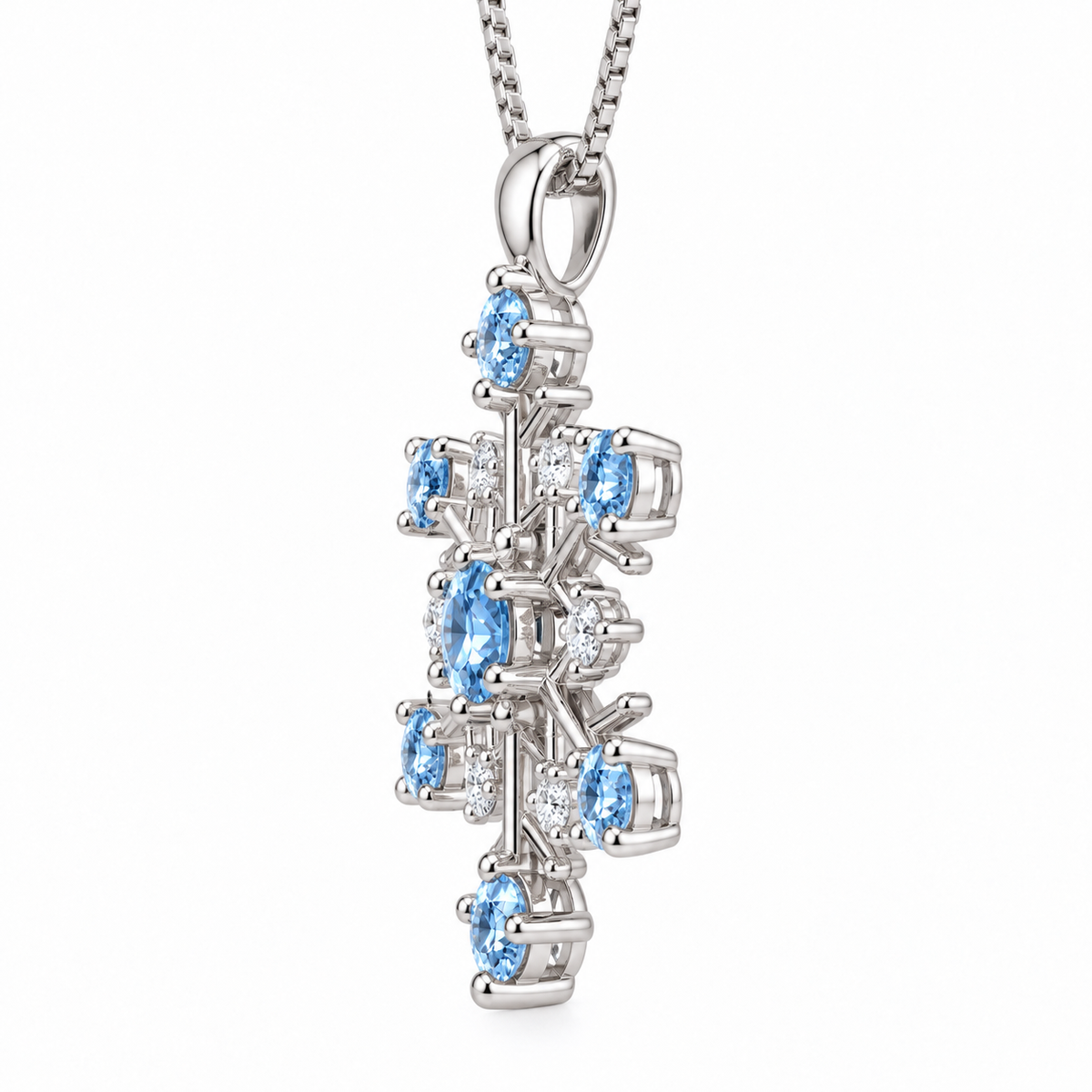 Side profile of an icy blue moissanite snowflake pendant necklace highlighting the raised gemstone prong settings, polished sterling silver branches, openwork snowflake construction and delicate silver chain on a pure white background.