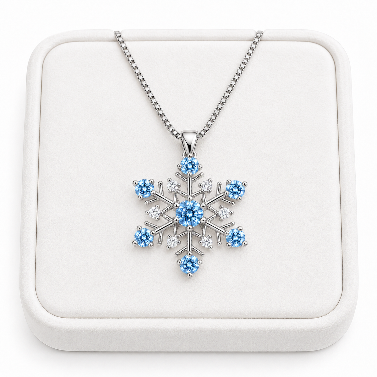 Phimsera icy blue moissanite snowflake necklace displayed on a premium white velvet jewelry tray against a pure white background, featuring a sparkling blue center gemstone, six icy blue moissanite tips, clear cubic zirconia accents and delicate sterling silver chain.