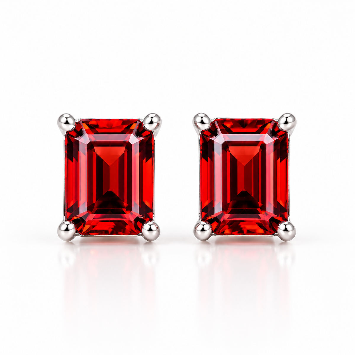 Natural red garnet emerald cut stud earrings featuring two 6x8mm rectangular crimson-red gemstones in polished 925 sterling silver four-prong settings against a pure white background.