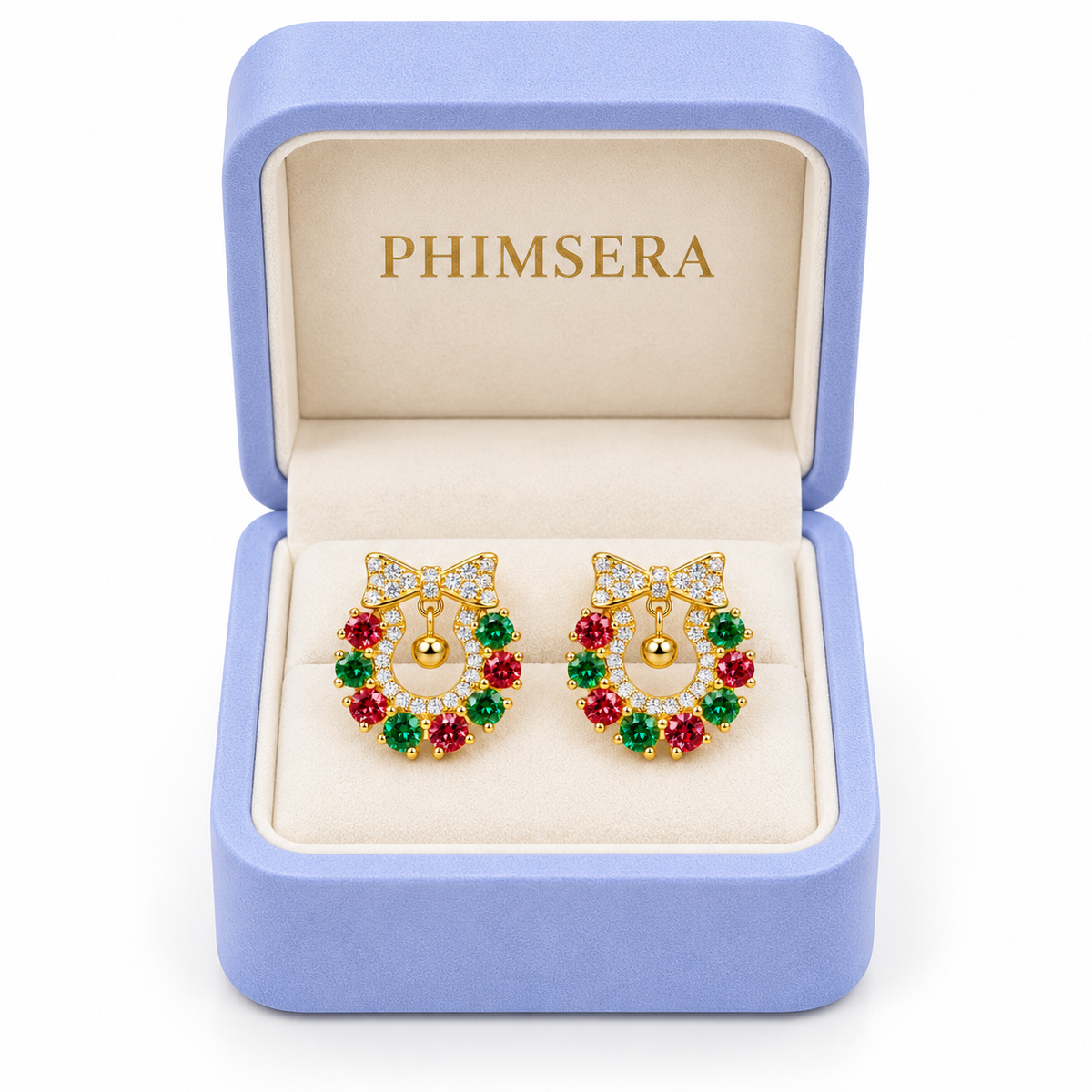 Red and green moissanite Christmas wreath earrings displayed inside an open periwinkle Phimsera jewelry gift box with an ivory interior and gold PHIMSERA lettering against a white background.