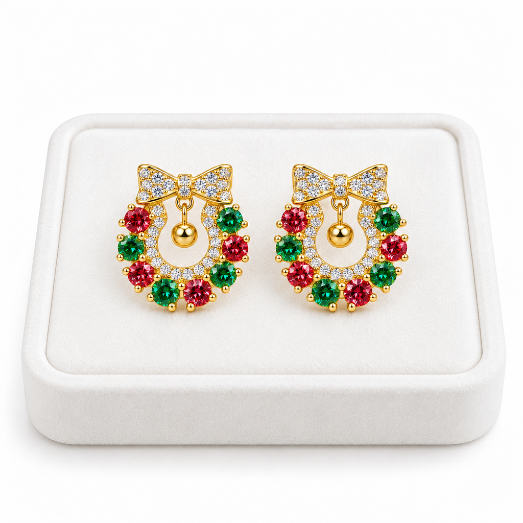 Pair of red and green 3mm moissanite Christmas wreath earrings displayed on a premium white velvet jewelry tray with gold-plated bows, white CZ accents and a pure white background.