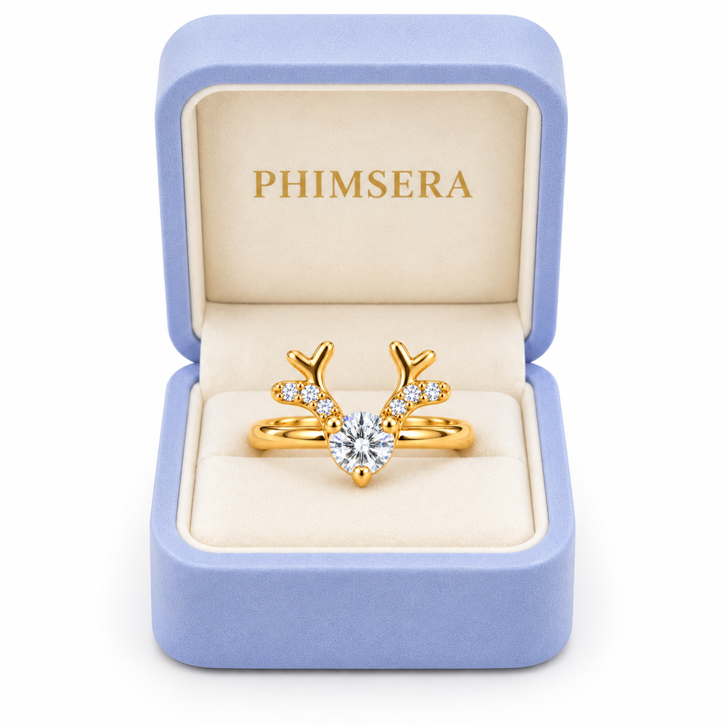 Phimsera white moissanite Christmas reindeer antler ring displayed inside an open periwinkle jewelry gift box with ivory interior and gold Phimsera branding.