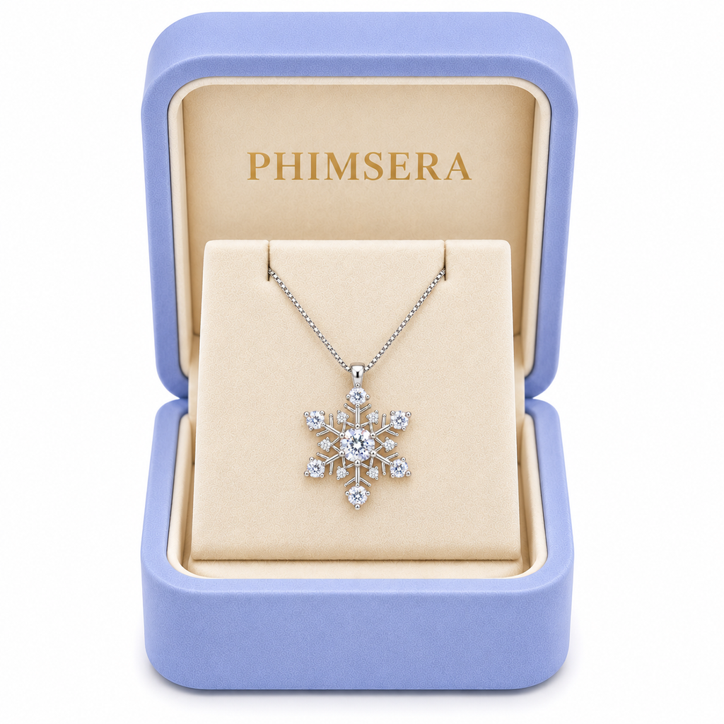 White moissanite snowflake necklace displayed inside a periwinkle Phimsera jewelry gift box with ivory velvet interior and gold PHIMSERA lettering, featuring a delicate silver chain and sparkling gemstones.